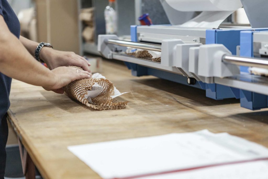 Mitarbeiter verpackt frisches Brot in Folie mit professioneller Verpackungsmaschine in Bäckerei
