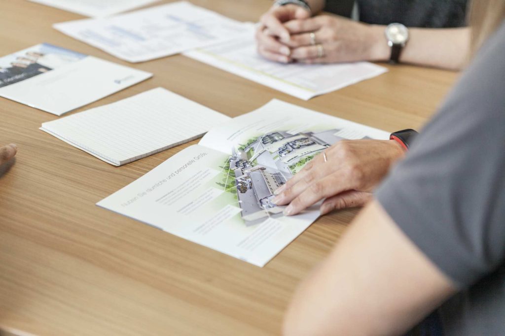 Geschäftsleute betrachten Baupläne und Architekturzeichnungen während einer Besprechung am Holztisch