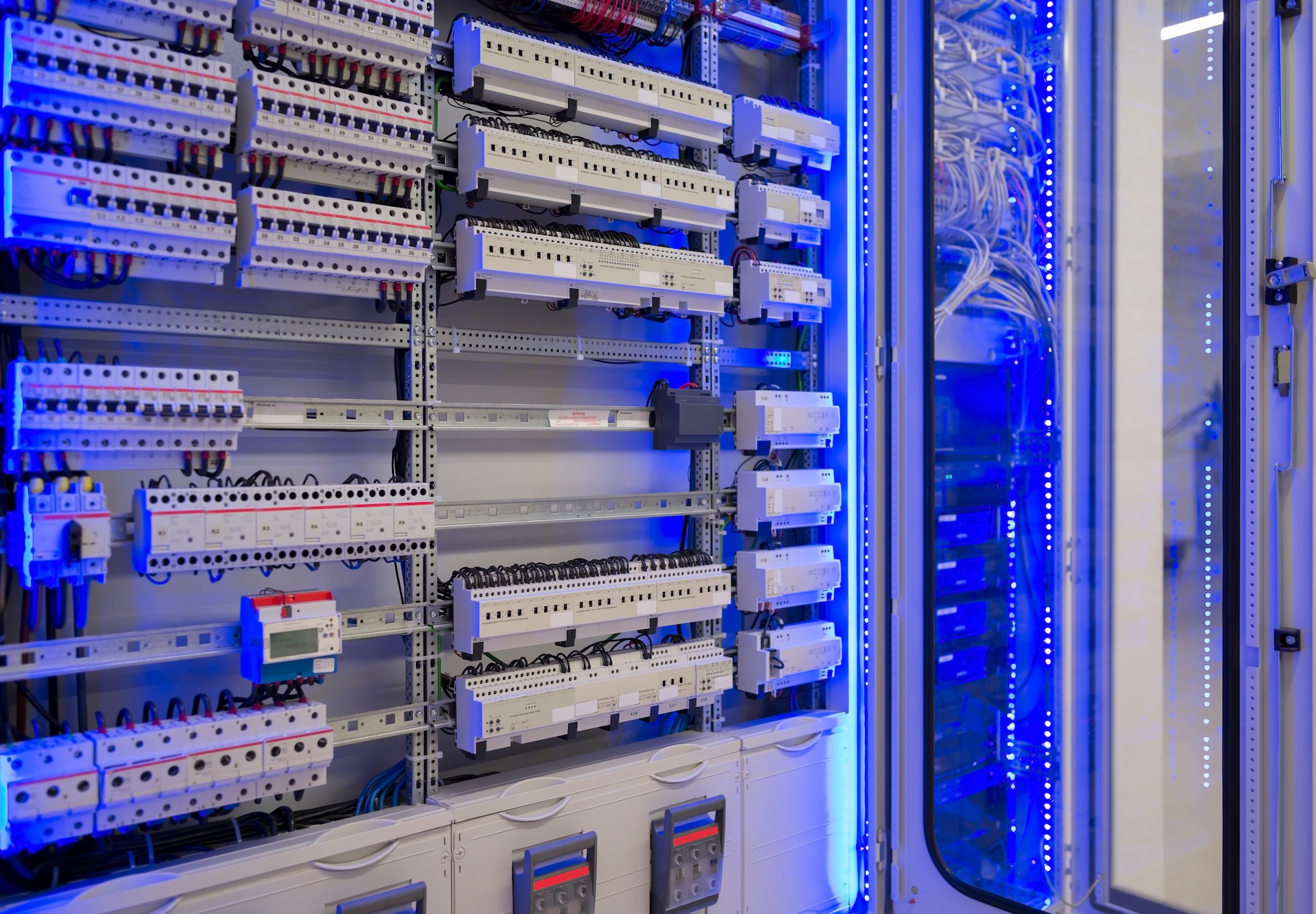 Elektrischer Schaltschrank mit Sicherungen, Relais und blauer LED-Beleuchtung in einem Serverschrank