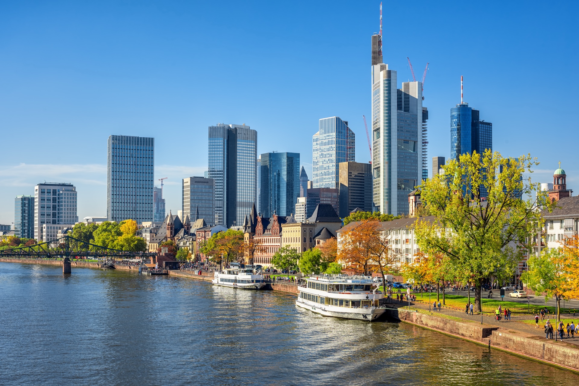 Frankfurter Skyline mit Wolkenkratzern und Ausflugsbooten auf dem Main bei herbstlichem Sonnenschein