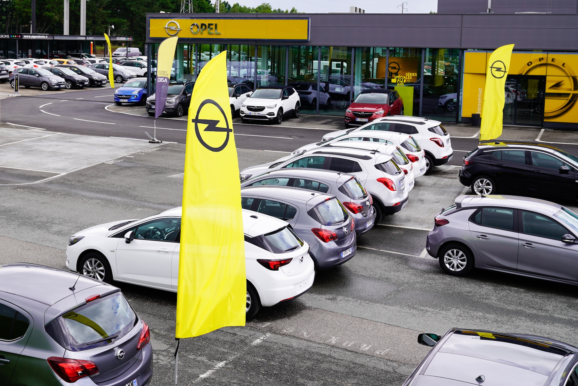 Opel Autohaus mit gelben Werbefahnen und Neuwagen auf dem Verkaufsplatz