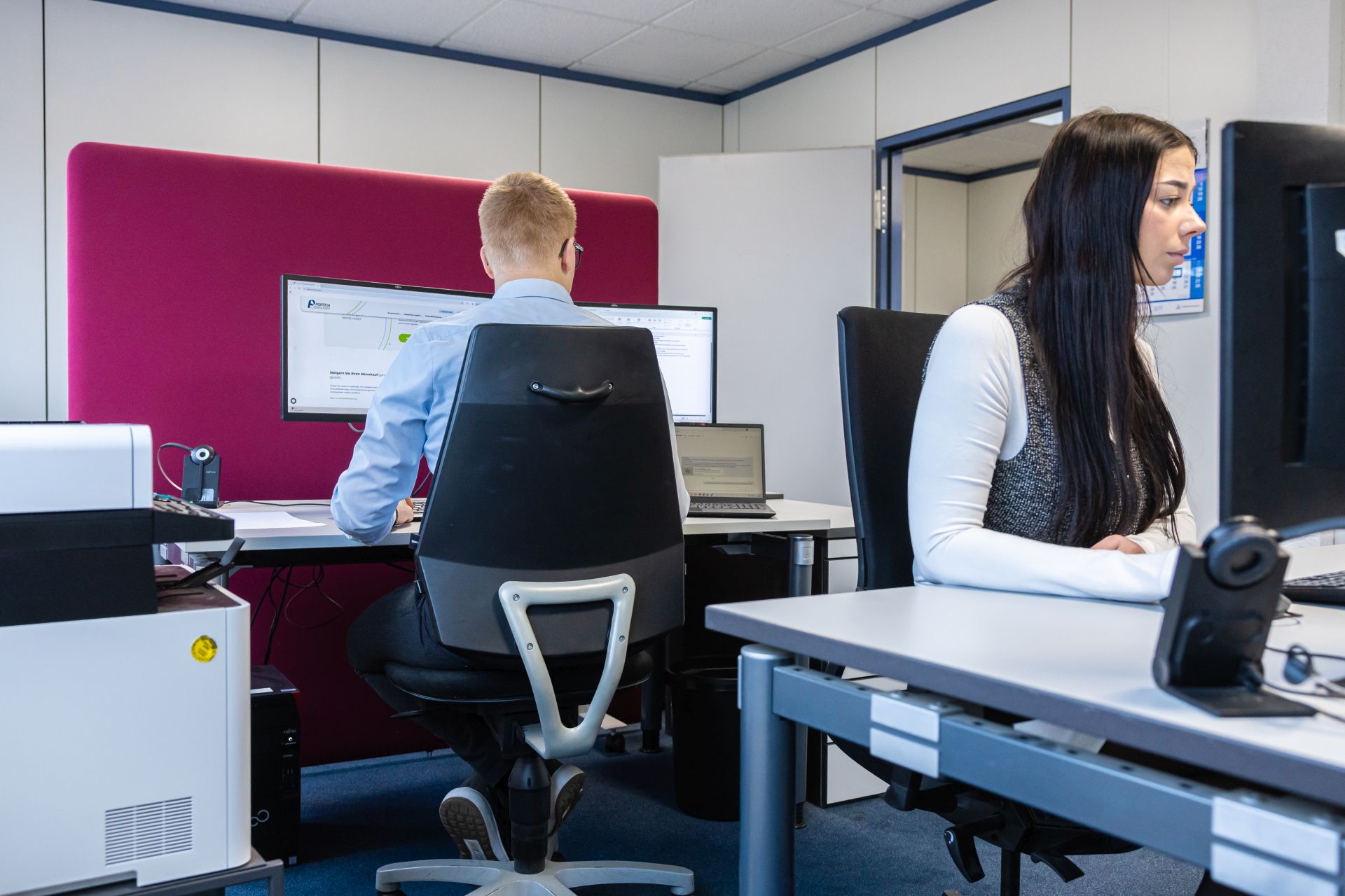 Zwei Mitarbeiter arbeiten konzentriert an Computern in einem modernen Großraumbüro mit ergonomischen Stühlen